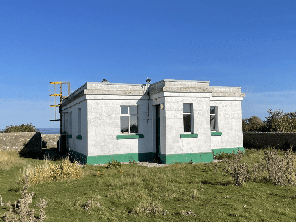 A small single story building, Flat Holm Cottage, surrounded by grass.