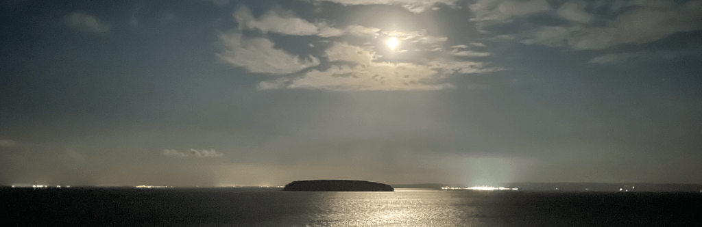 Steep Holm island at night with a moon lit above the island.